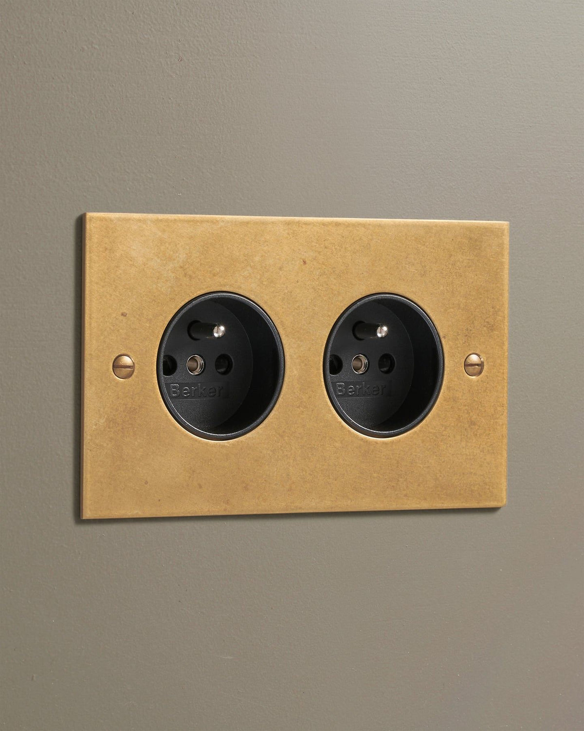 An oblique view of a classic French-style twin plug socket in a mottled aged brass finish. TEST