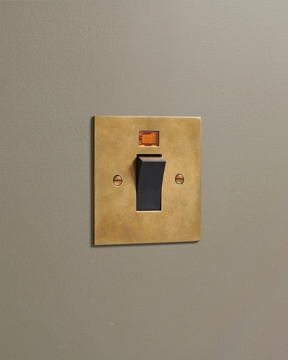 An oblique view of a classic 45 amp cooker switch in a warm burnished brass finish. TEST