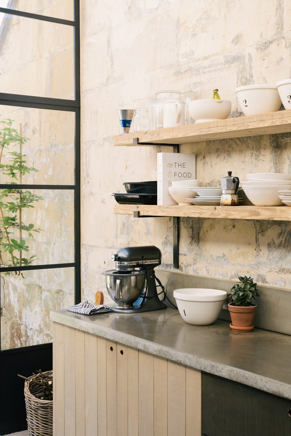 a seamless Bath stone wall with elegant Crittal style windows and simple Sebastian Cox cupboards