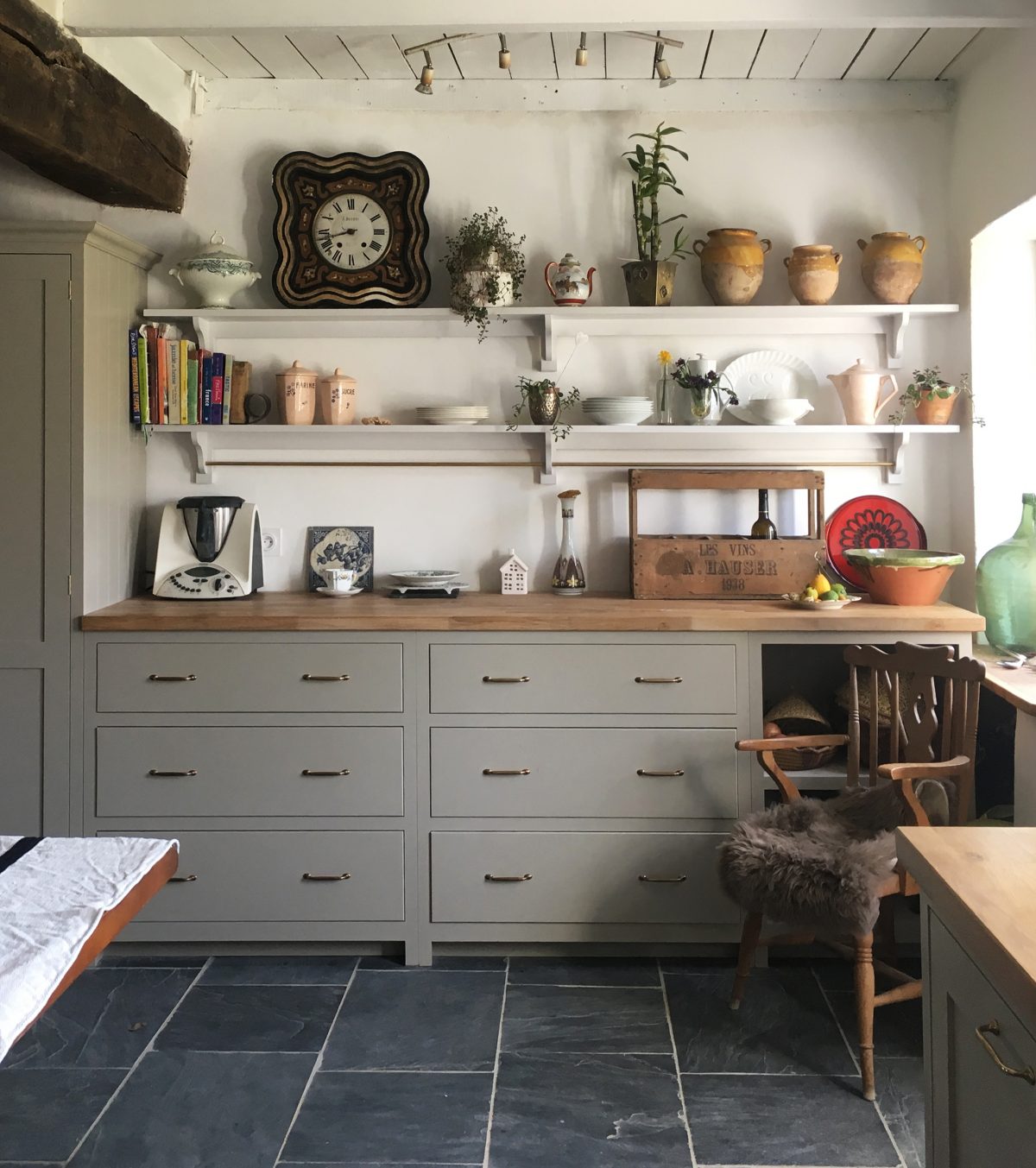 Mushroom cupboards, natural dark stone floors, wooden worktops and brass handles.