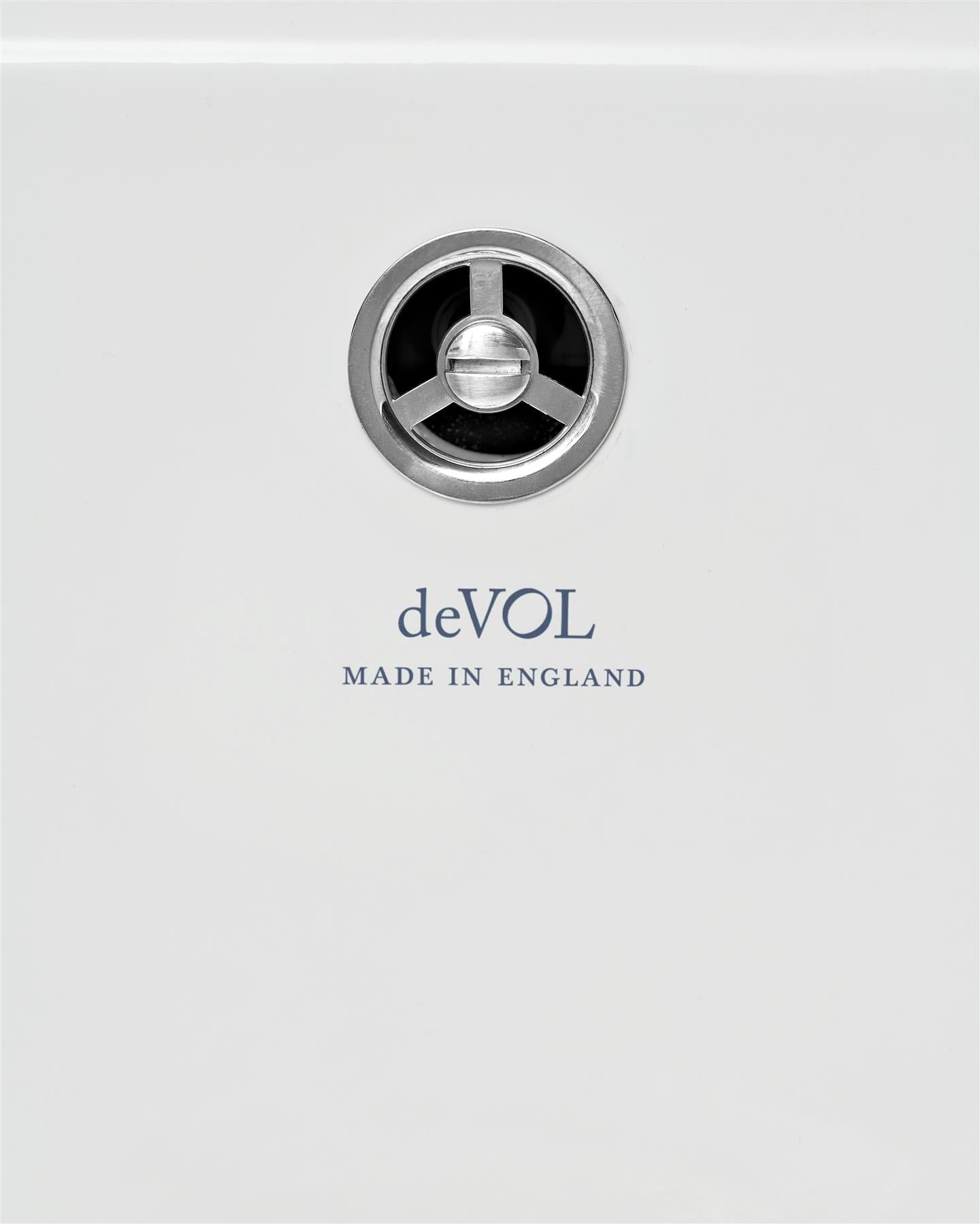 A round sink overflow cap in a chrome finish, fitted to a ceramic sink with the words 'deVOL, Made in England' printed in the glaze below.