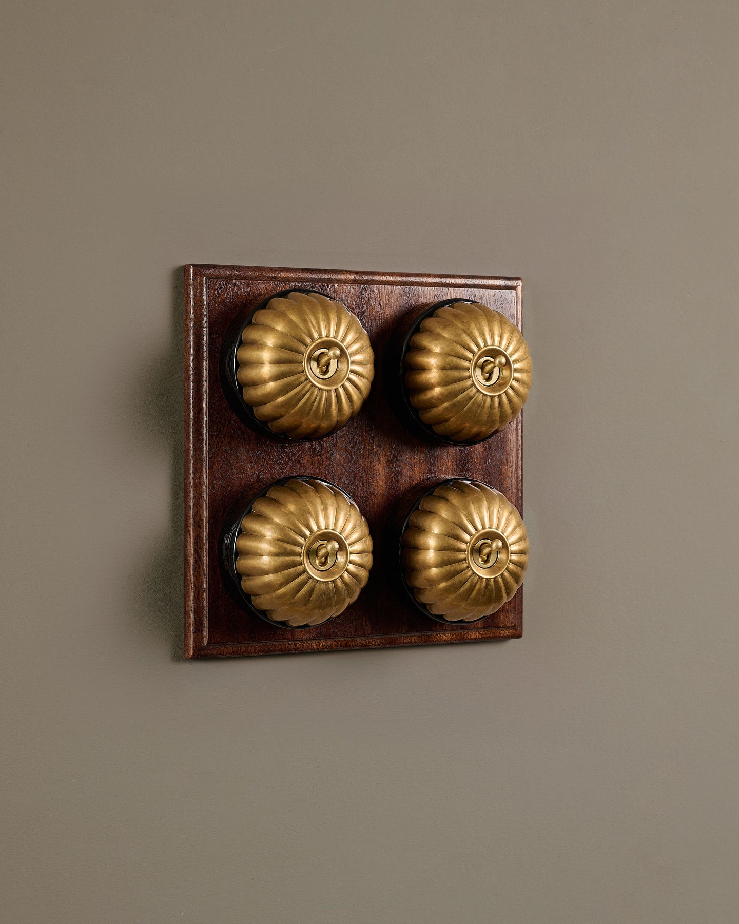 The Jelly Toggle Switch (4 Gang Bank & Mahogany Finish Pattress) - Aged Brass with Black Base.