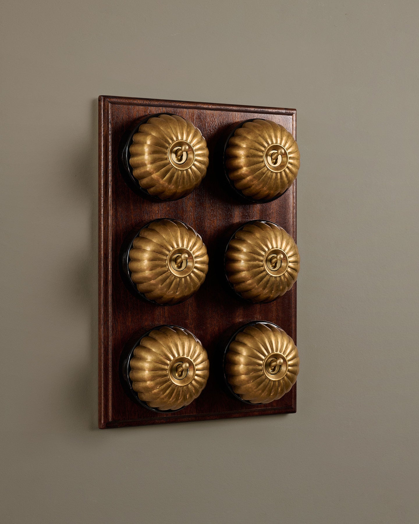 The Jelly Toggle Switch (6 Gang & Mahogany Finish Pattress) - Aged Brass with Black Base.