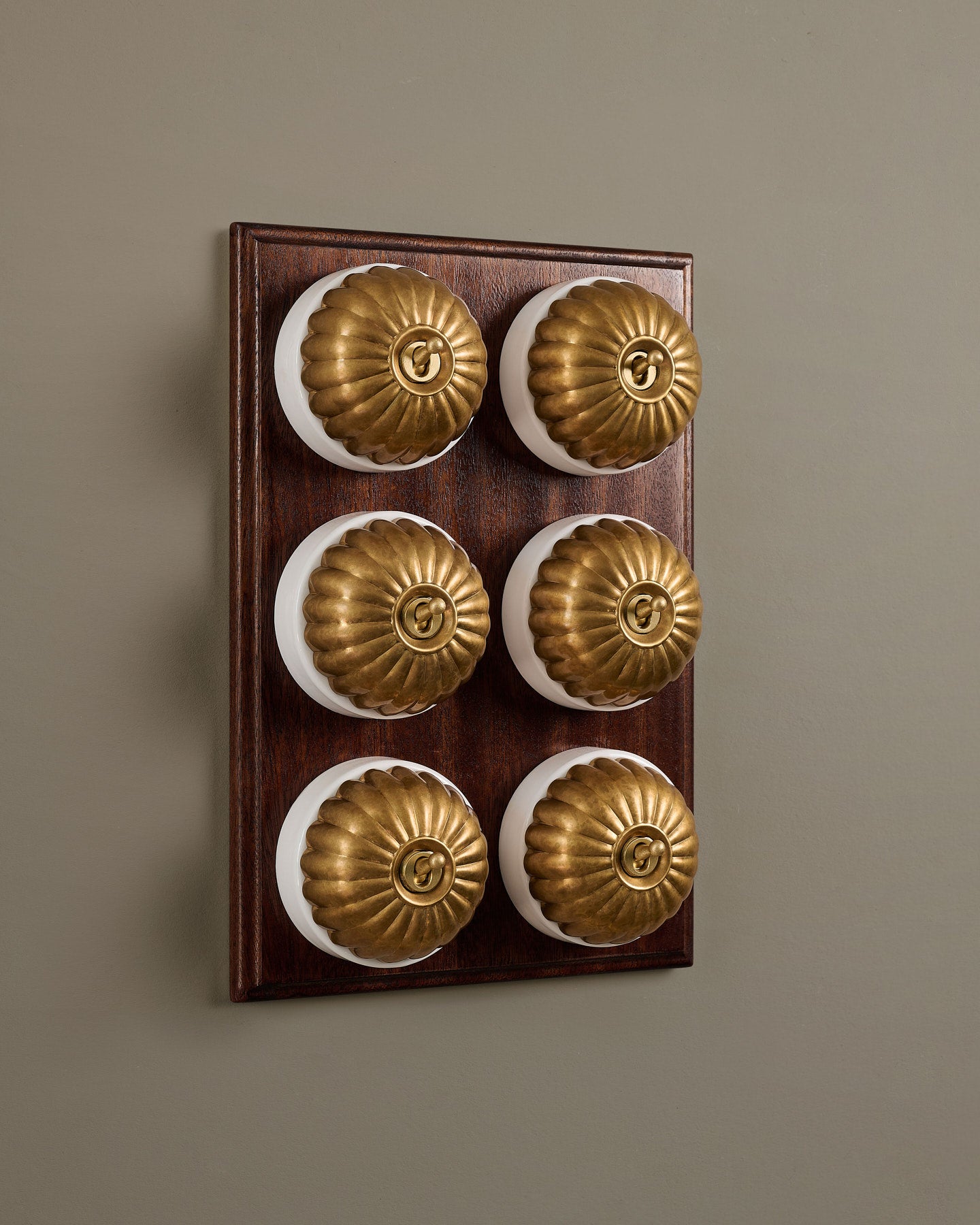 The Jelly Toggle Switch (6 Gang & Mahogany Finish Pattress) - Aged Brass with White Base.