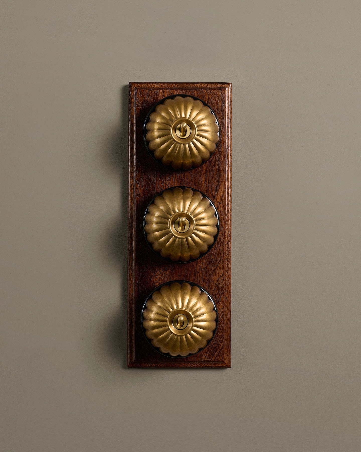 The Jelly Toggle Switch (3 Gang & Mahogany Finish Pattress) - Aged Brass with Black Base.