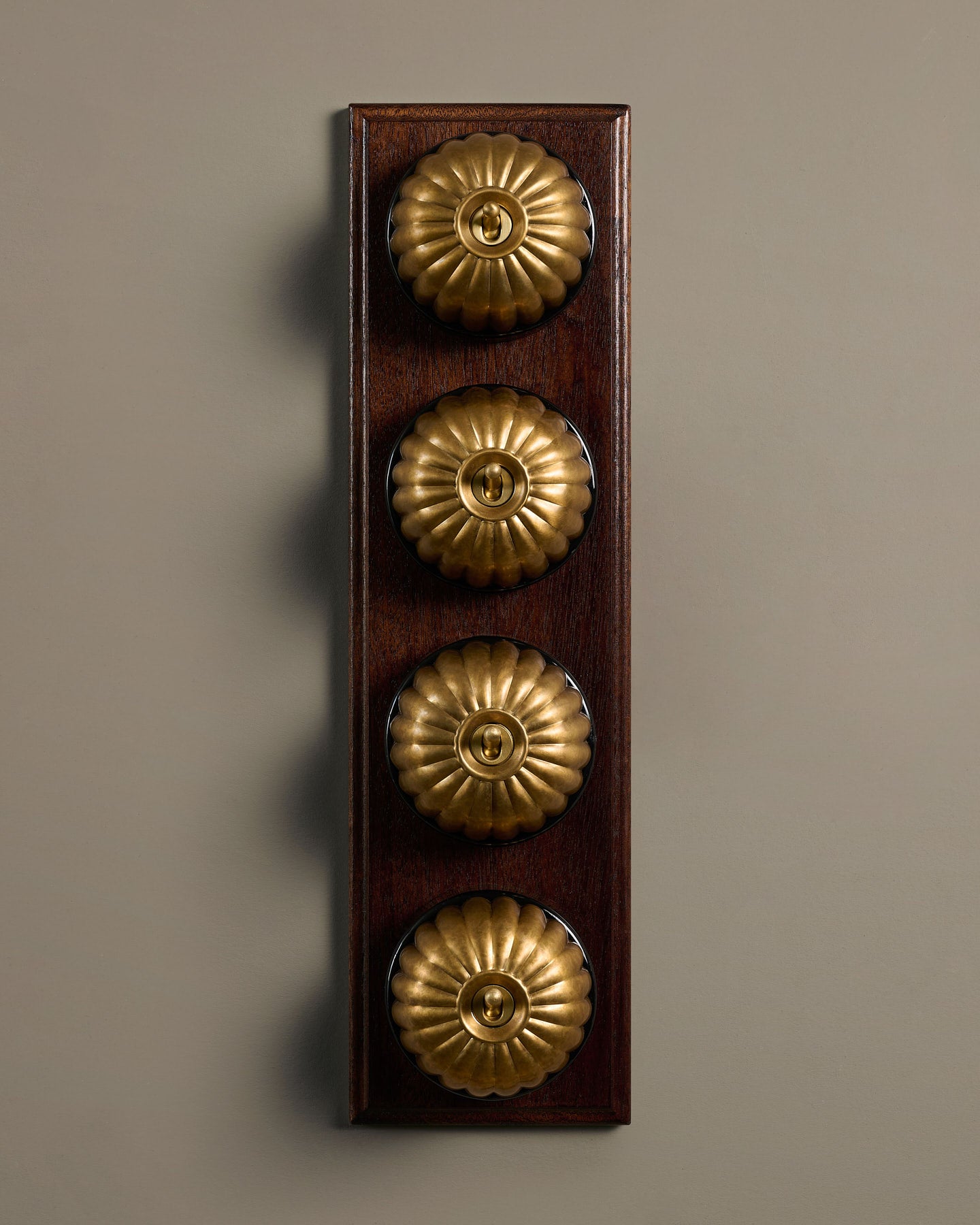 The Jelly Toggle Switch (4 Gang Row & Mahogany Finish Pattress) - Aged Brass with Black Base.