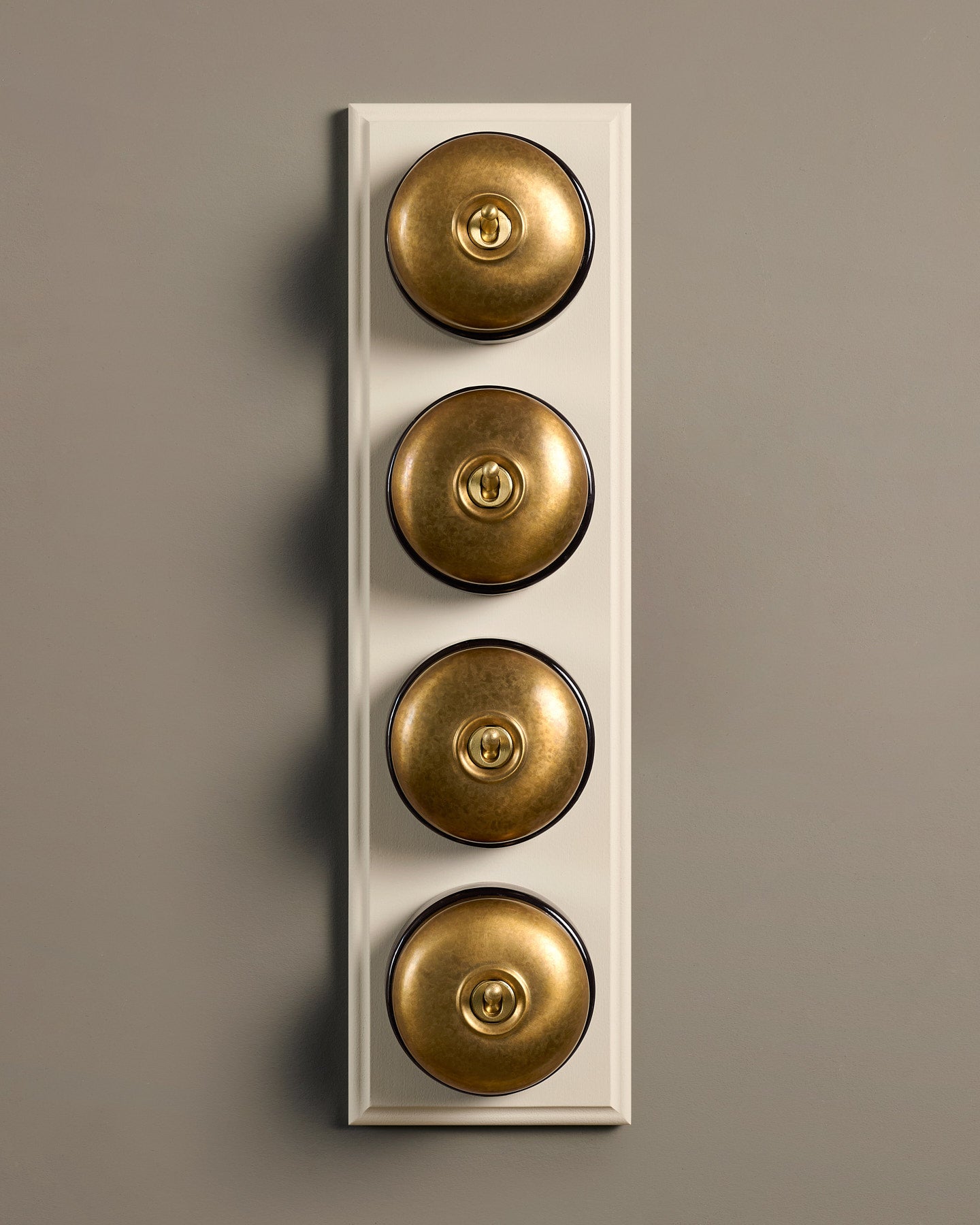 The Dolly Toggle Switch (4 Gang Row & Primed Maple Pattress) - Aged Brass with Black Base.