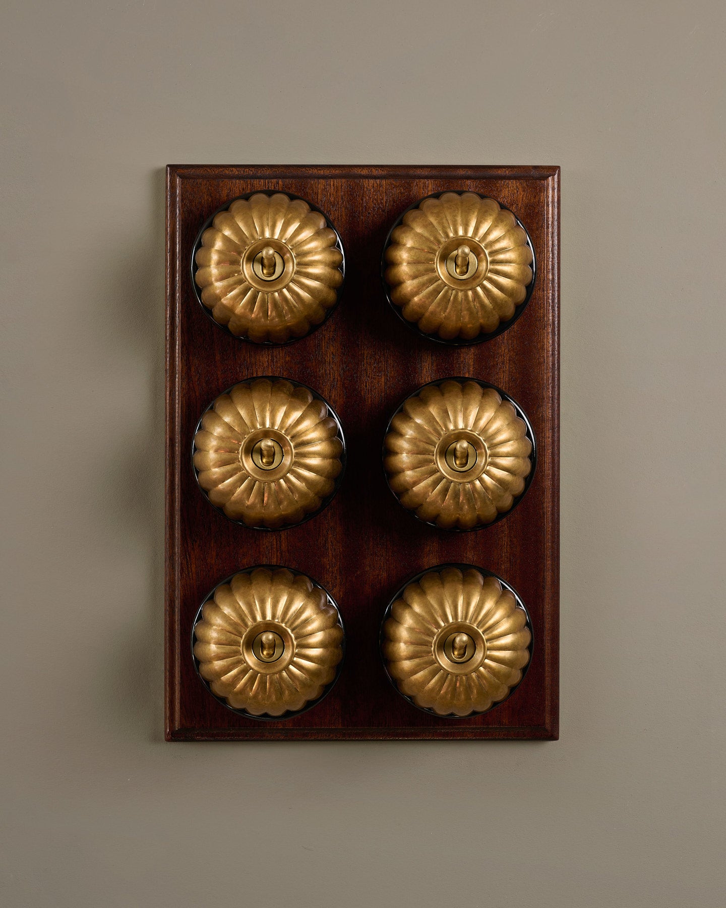 The Jelly Toggle Switch (6 Gang & Mahogany Finish Pattress) - Aged Brass with Black Base.
