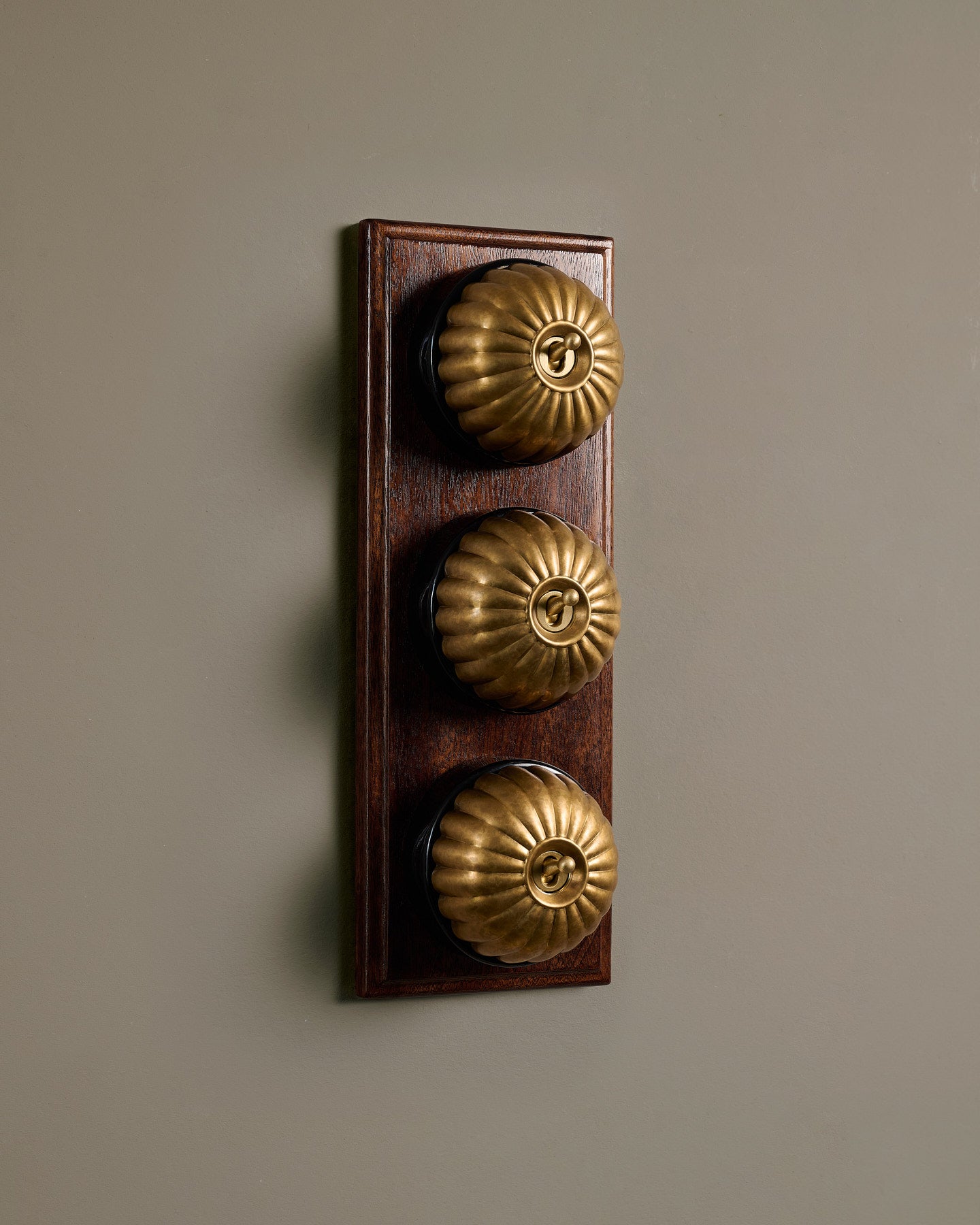 The Jelly Toggle Switch (3 Gang & Mahogany Finish Pattress) - Aged Brass with Black Base.