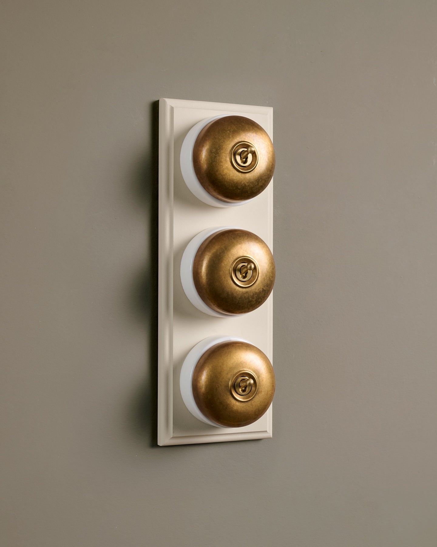 The Dolly Toggle Switch (3 Gang & Primed Maple Pattress) - Aged Brass with White Base.