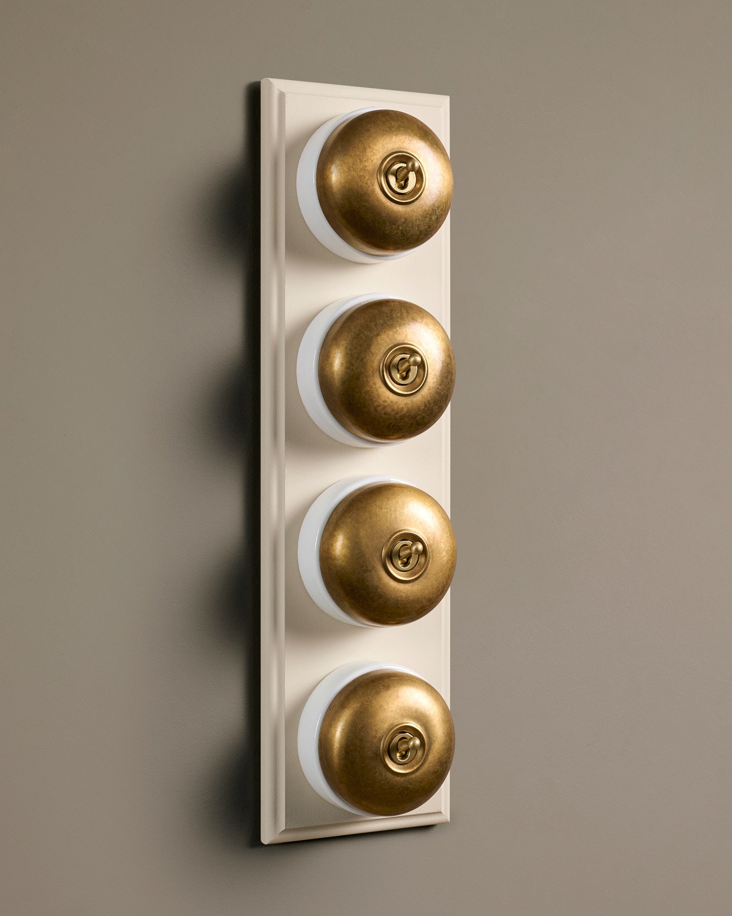 The Dolly Toggle Switch (4 Gang Row & Primed Maple Pattress) - Aged Brass with White Base.