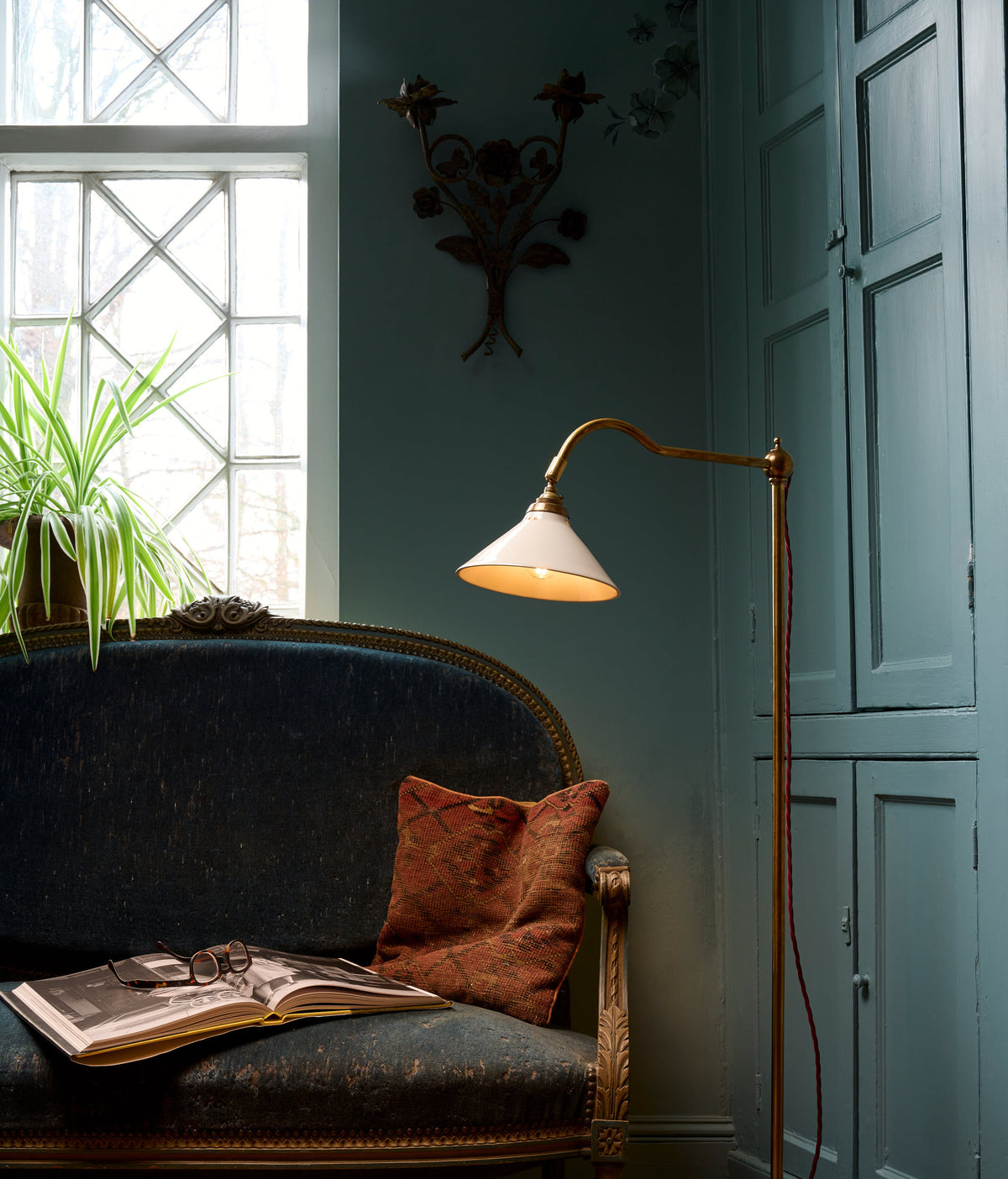 In a quiet corner of an elegant, royal blue reading room sits a charming grand tour reading lamp.