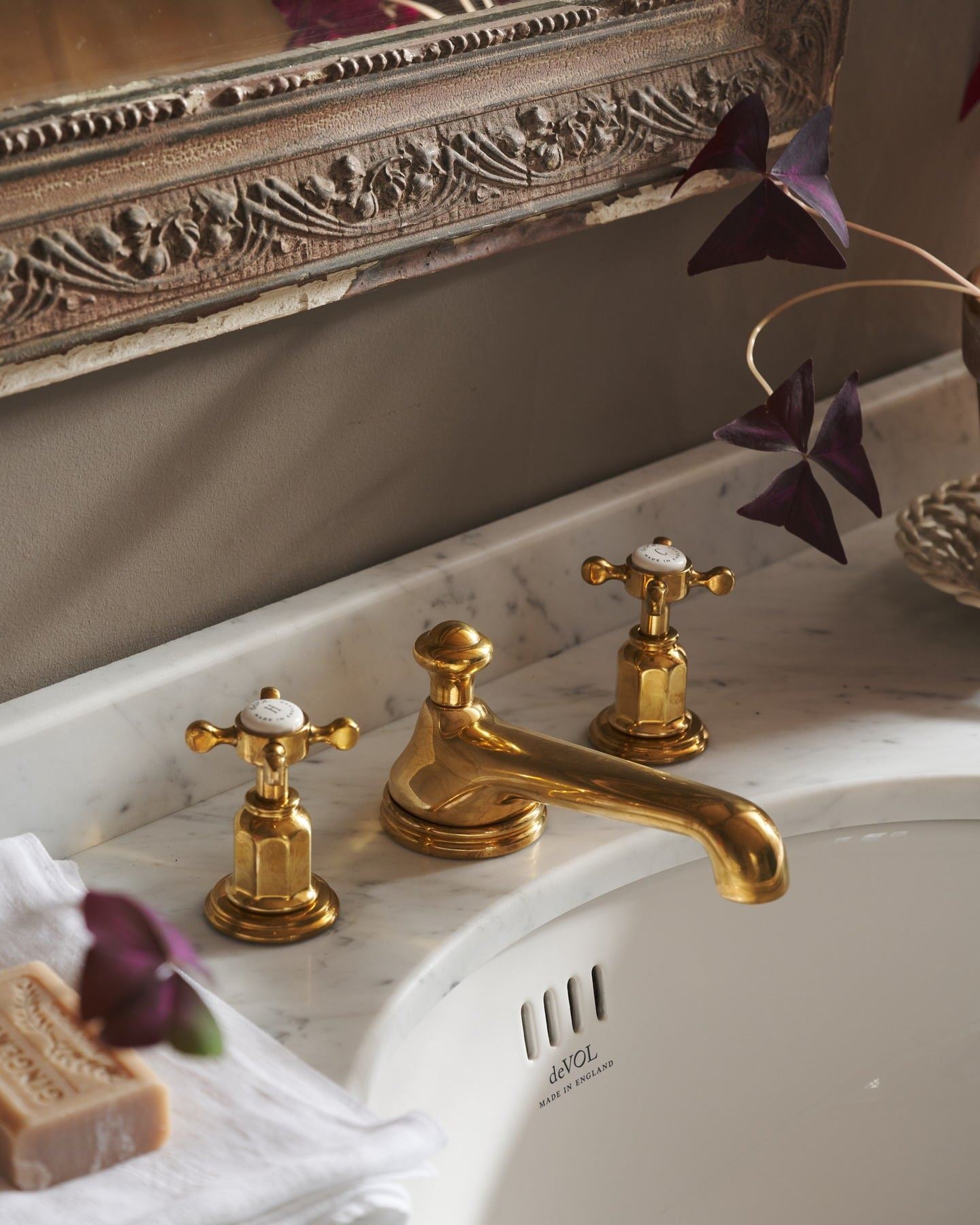 An oblique view of an aged brass mixer tap with crosshead handles for a bathroom basin sink.