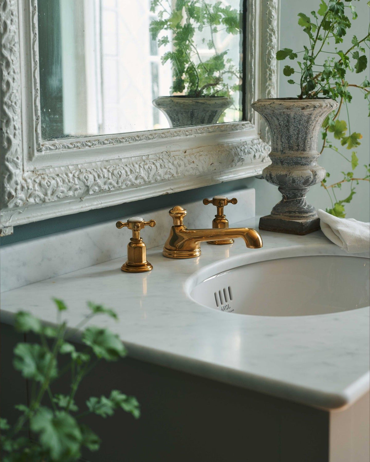 An oblique view of an aged brass mixer tap for a bathroom basin sink fitted to a mushroom painted washstand. TEST
