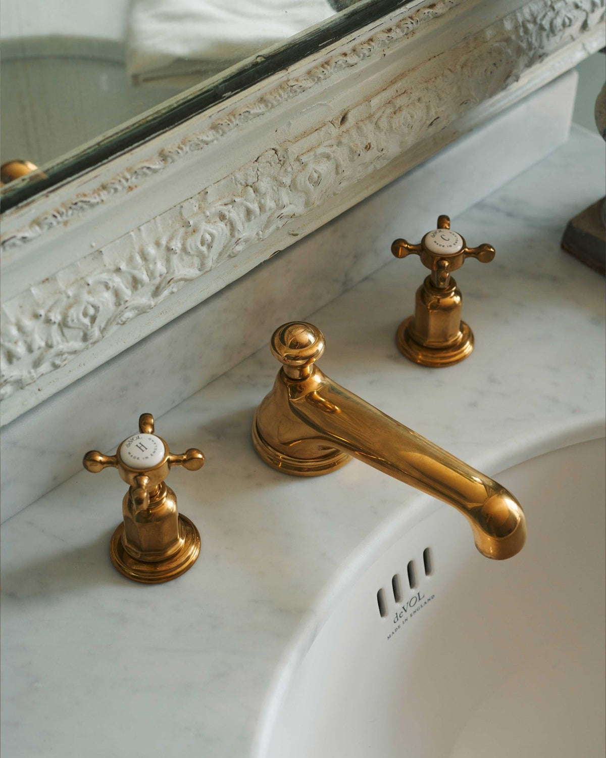 A close-up oblique view of an aged brass mixer tap for a bathroom basin sink. TEST