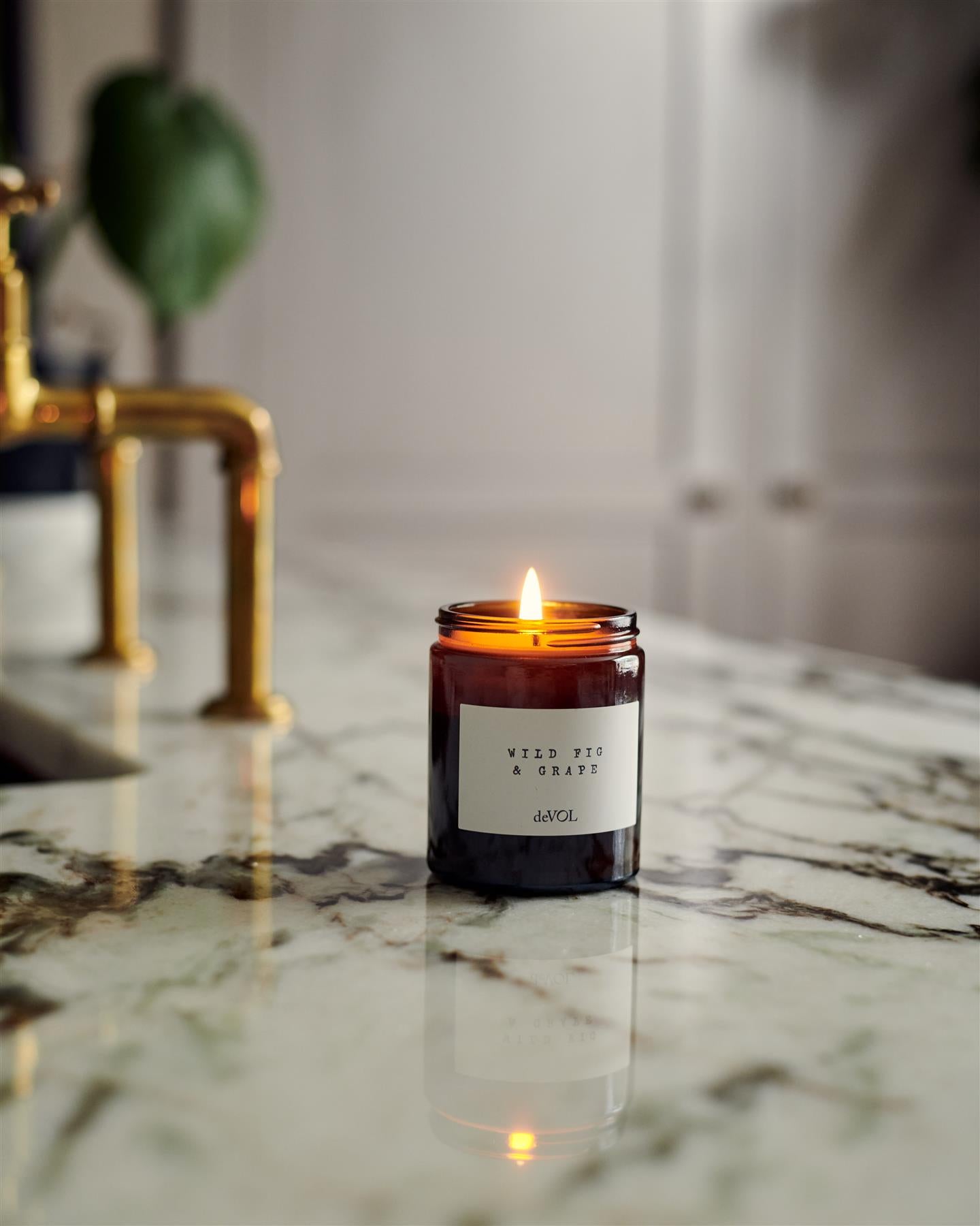 A collection of scented candles in brown glass jars with black lids in a vintage cupboard.