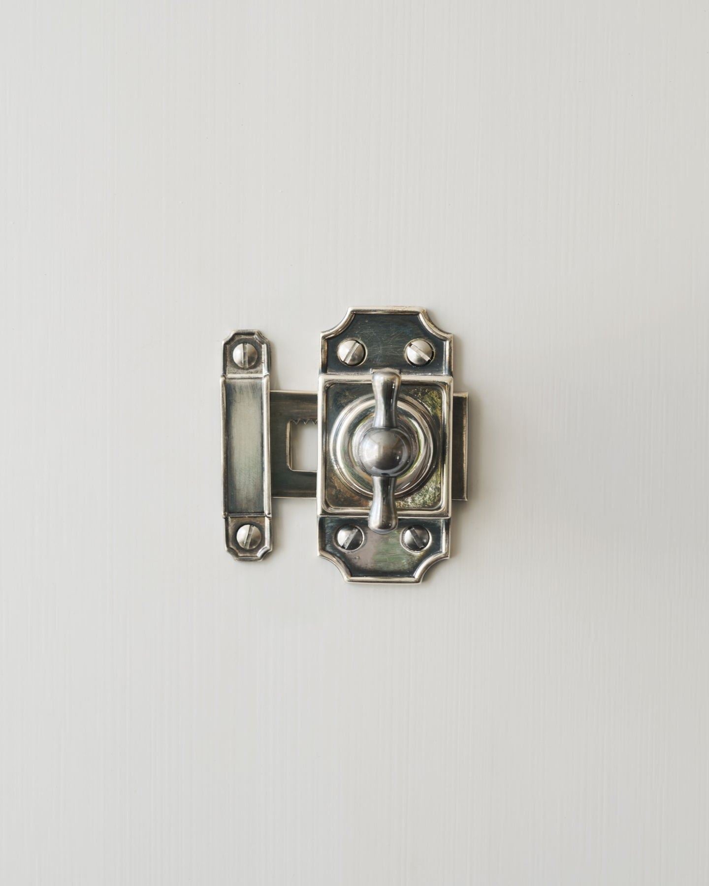 A Victorian-inspired rack and pinion cupboard catch in a tarnished silver finish.