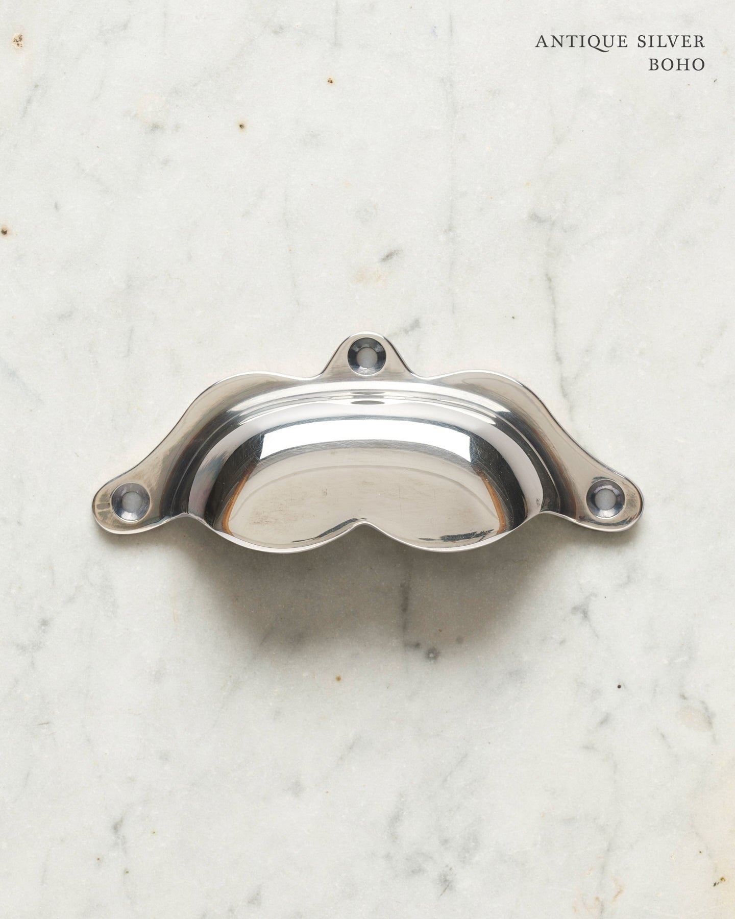 A bohemian-style cup handle for a kitchen cupboard or drawer with a tarnished silver finish.