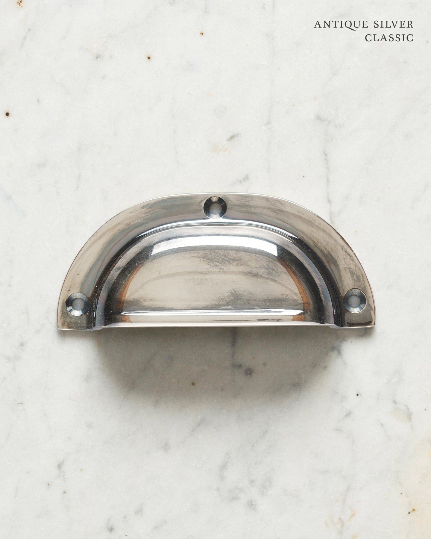 A classic cup handle for a kitchen cupboard or drawer with a tarnished silver finish.