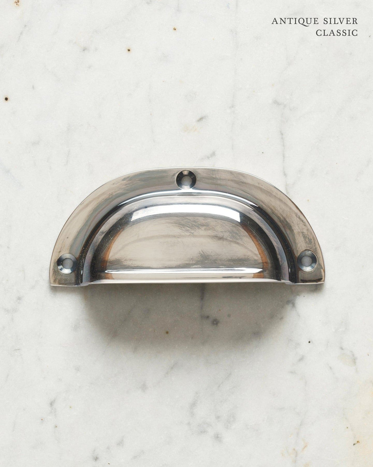 A classic cup handle for a kitchen cupboard or drawer with a tarnished silver finish. TEST