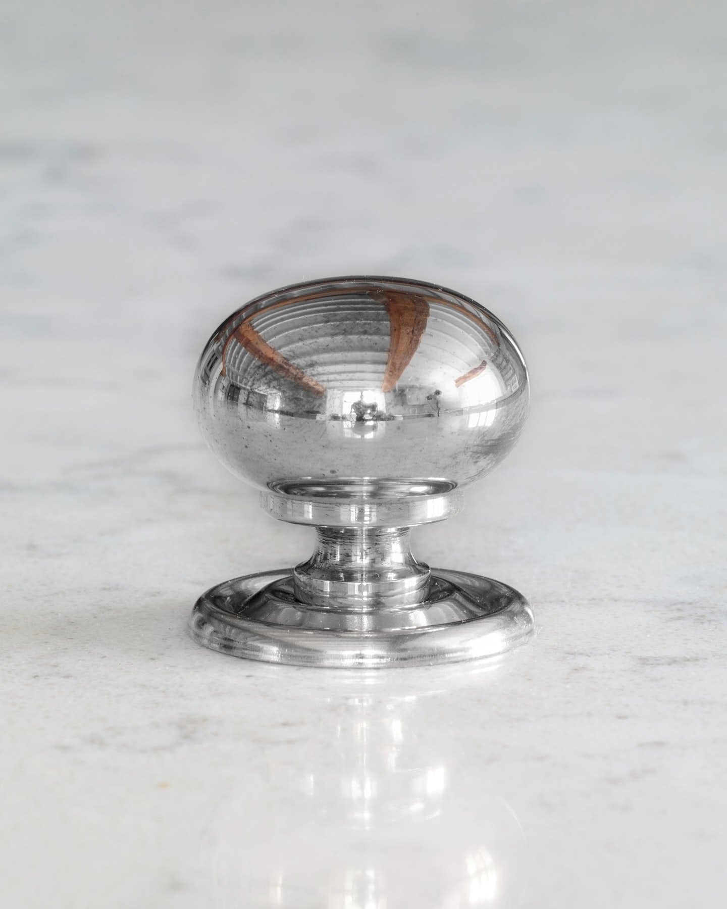 A 'Medium' round doorknob with a pressed backplate for a kitchen cupboard or drawer in a polished chrome finish.