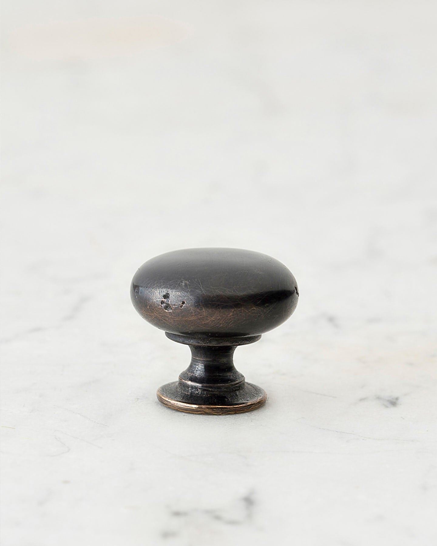 A 'Small' classic knob for a kitchen cupboard or drawer with a dark oxidised bronze finish and unique dented textures as if was made by an artisan blacksmith centuries ago.
