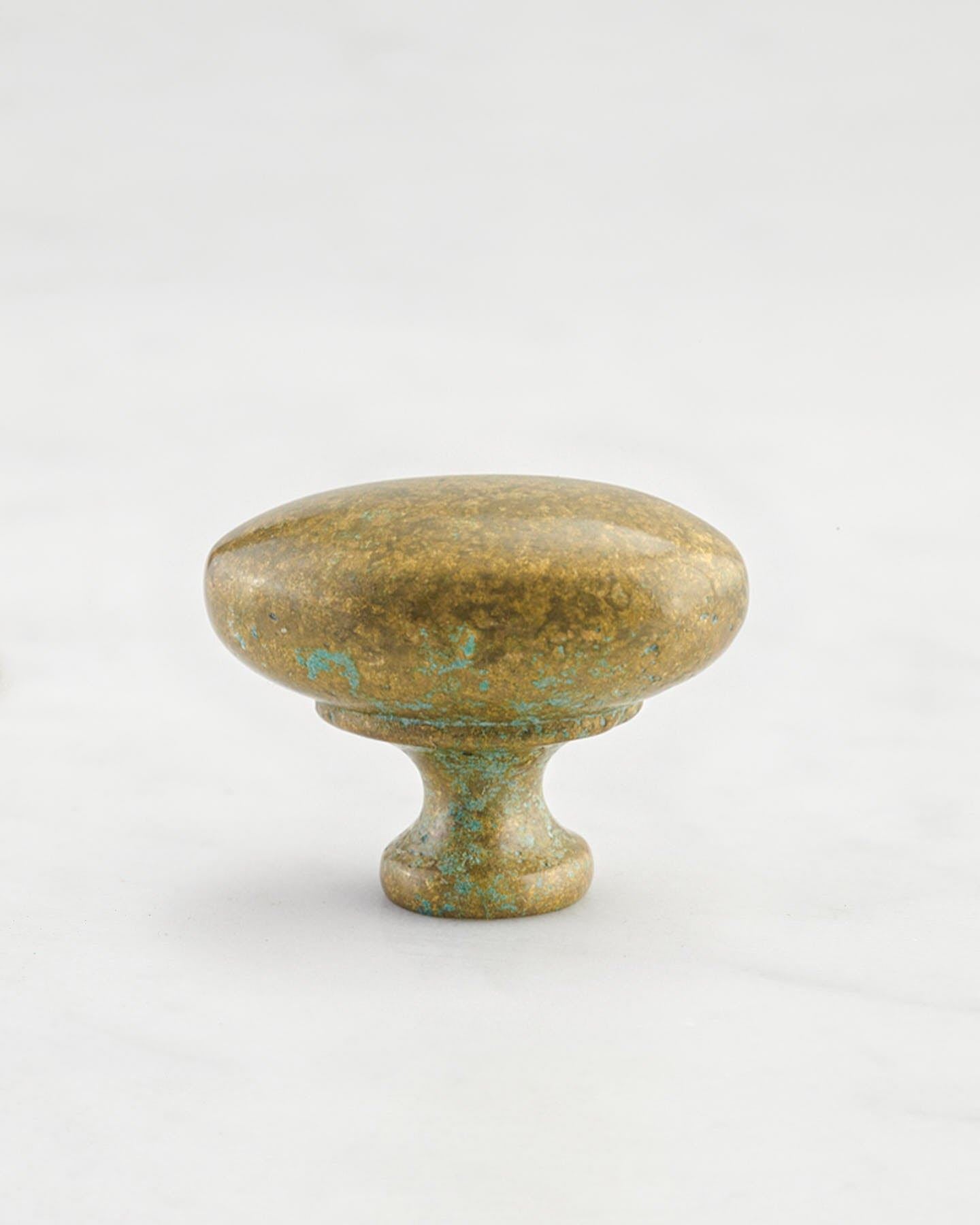 A 'Medium' oval-shaped knob for a kitchen cupboard or drawer with an aged verdigris brass finish and unique dented textures as if was made by an artisan blacksmith centuries ago.