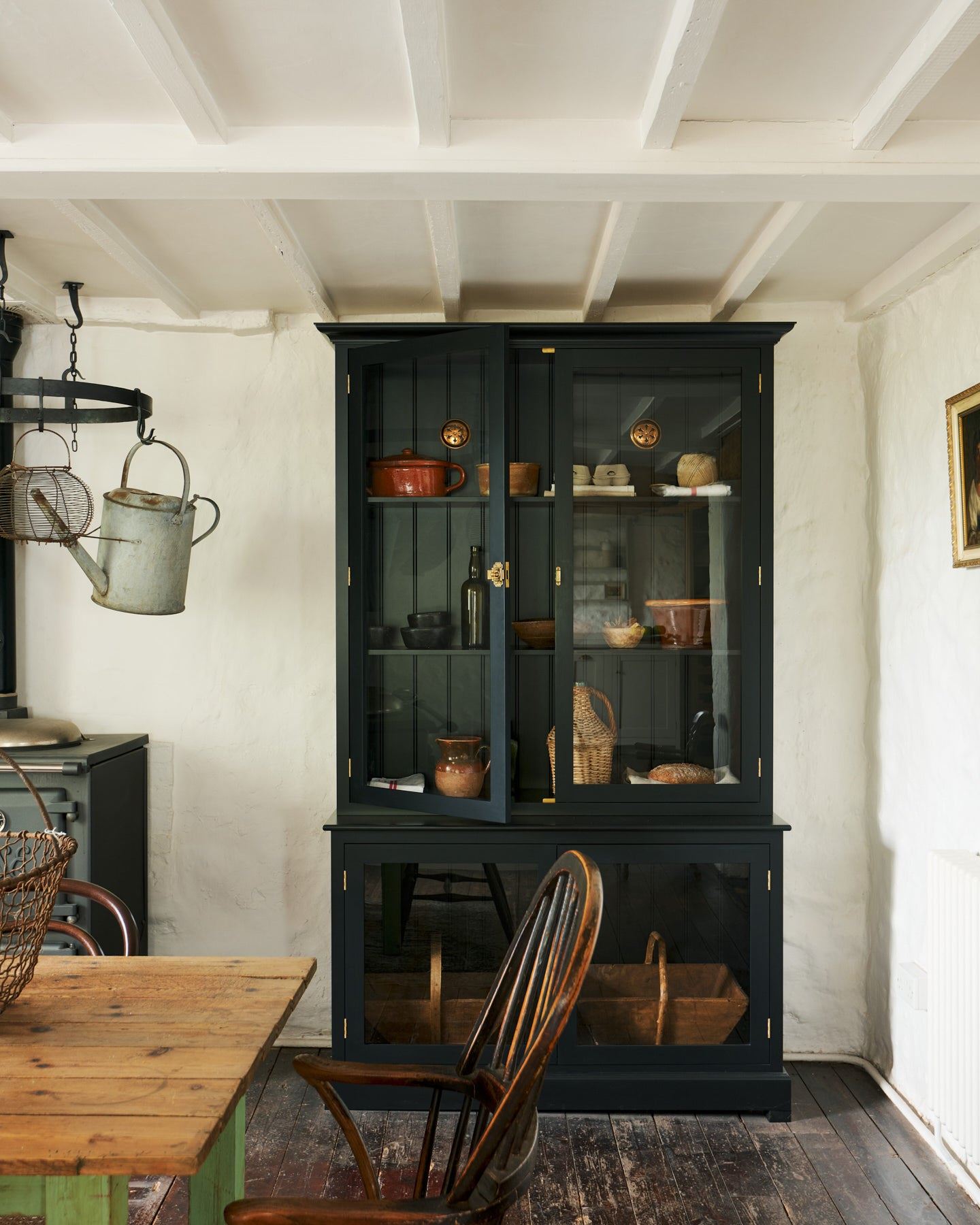 A tall museum-style black painted display cabinet with glazed doors and a pair of Victorian-inspired circular brass ventilation grilles with traditional decorative cutouts fitted to a tongue and groove-style back panel.