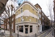 The deVOL St Johns Showroom in London is a corner, three floor, cream bricked building with strips of light beige painted exterior and a hand painted logo on top of the front door.
