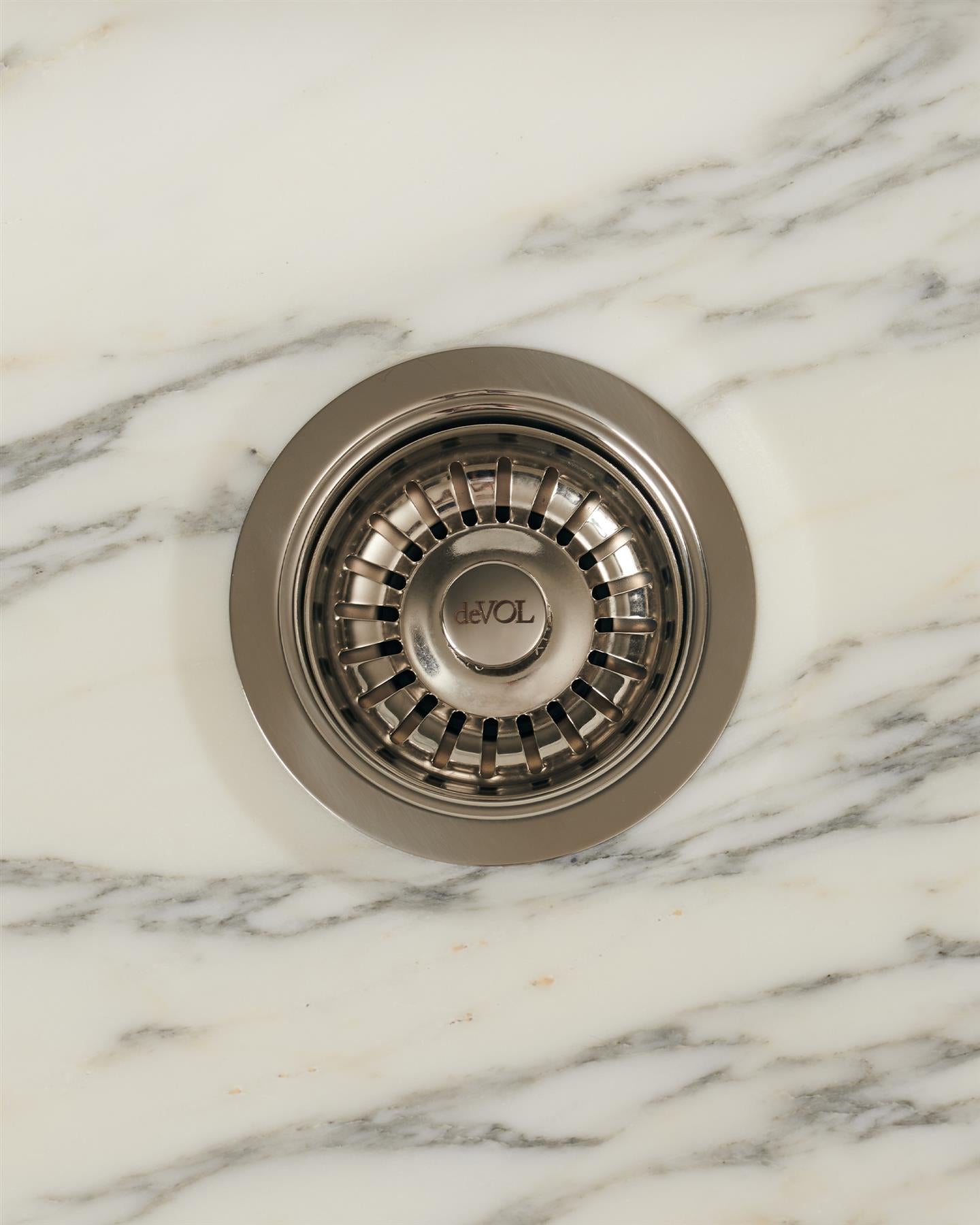 An overhead view of a basket waste strainer in a polished chrome finish, there is a small 'deVOL' logo in the middle of the central finial.