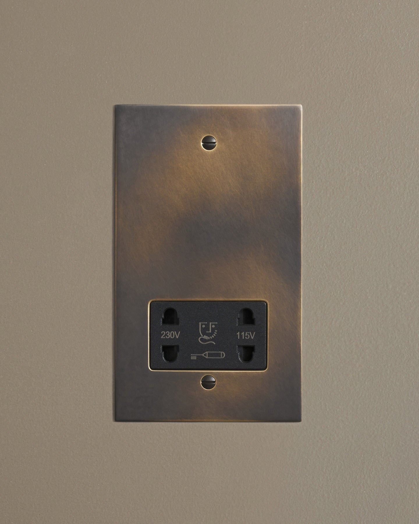 A straight-on view of a classic twin shaver socket in a dark oxidised brass finish.