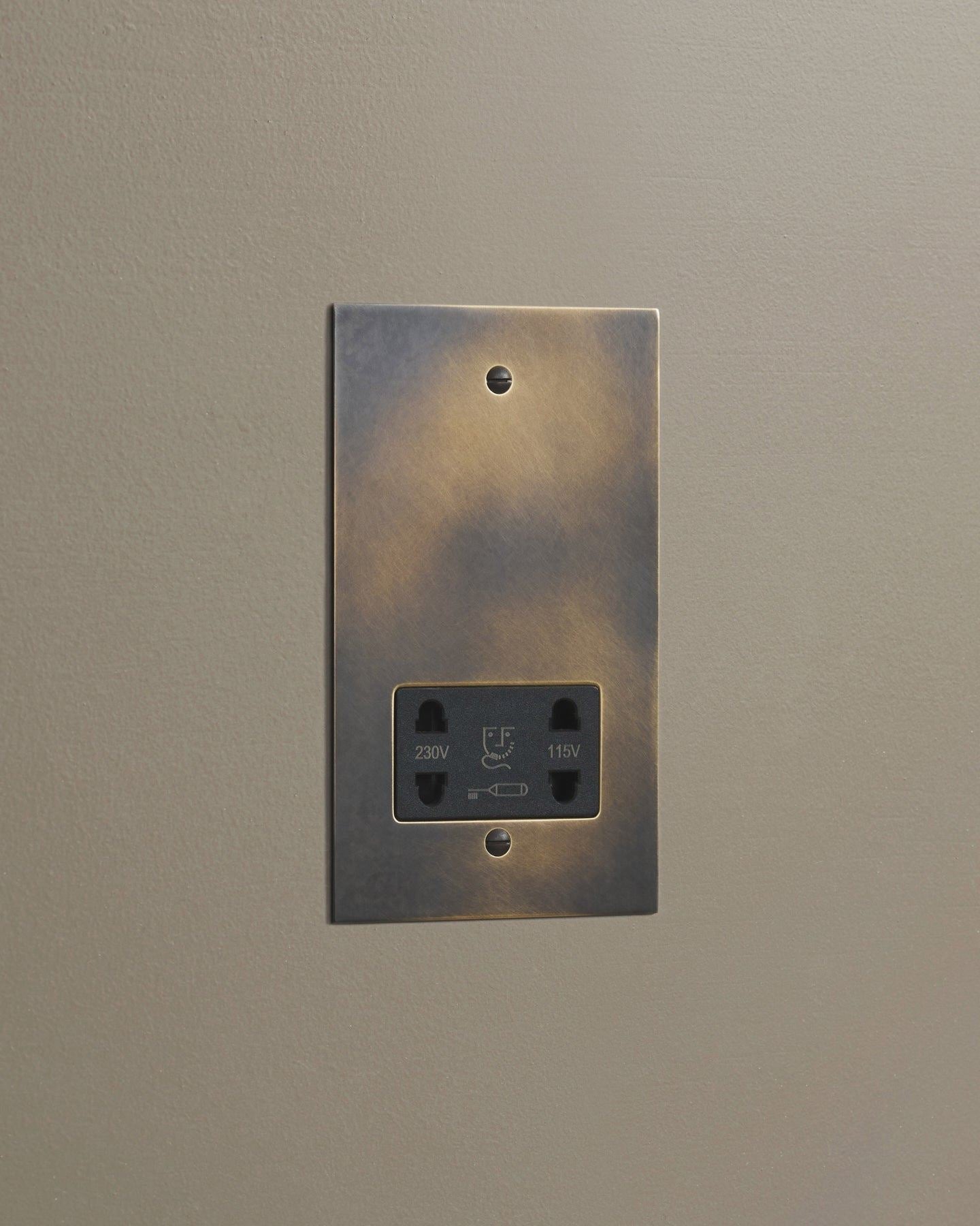An oblique view of a classic twin shaver socket in a dark oxidised brass finish.