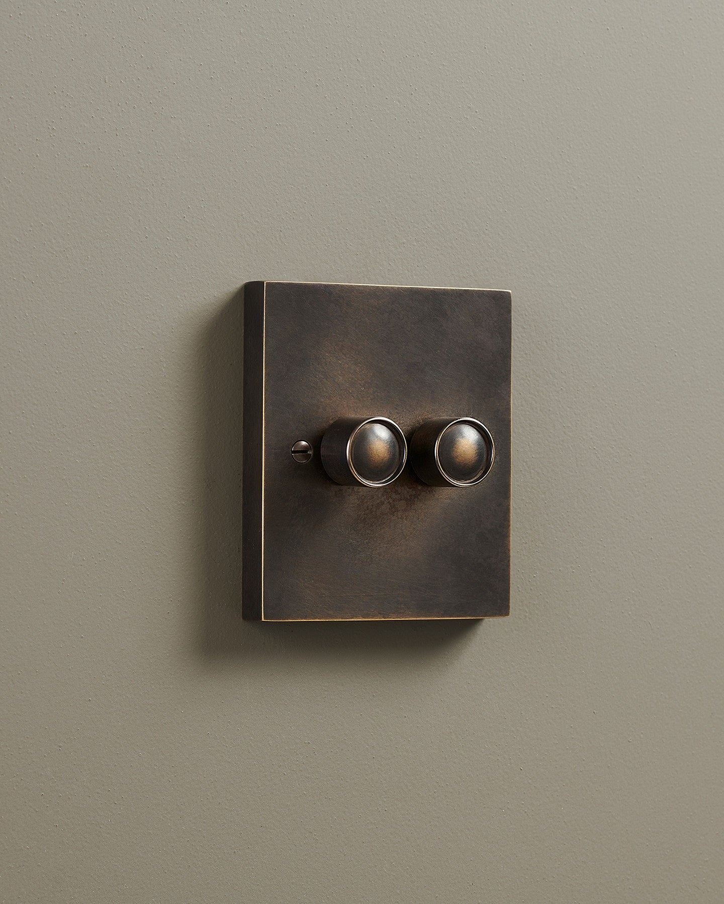 An oblique view of a 2 gang box dimmer switch in a dark oxidised brass finish.