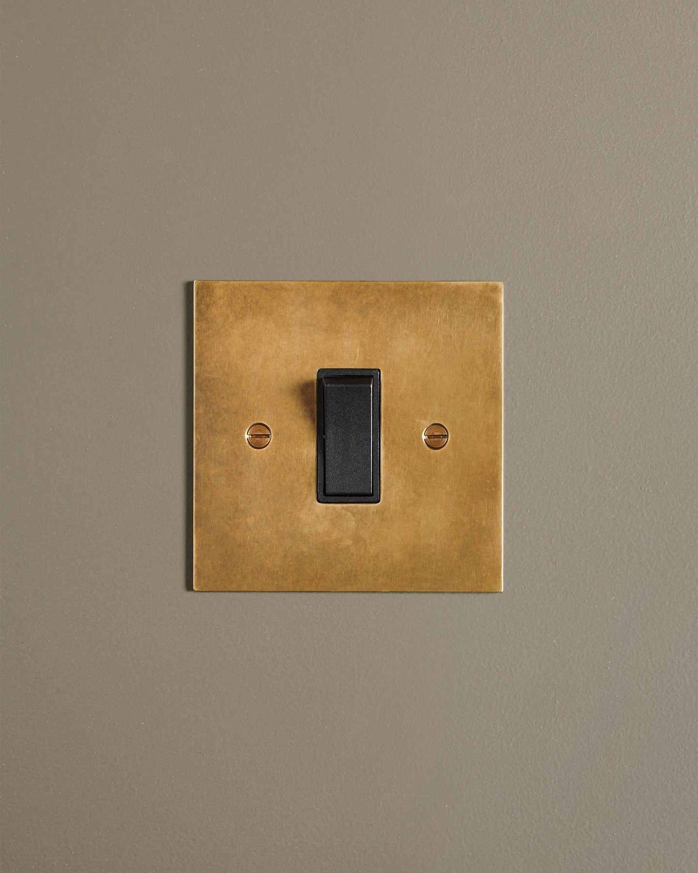 A straight-on view of a classic 20 amp switch in a warm burnished brass finish.