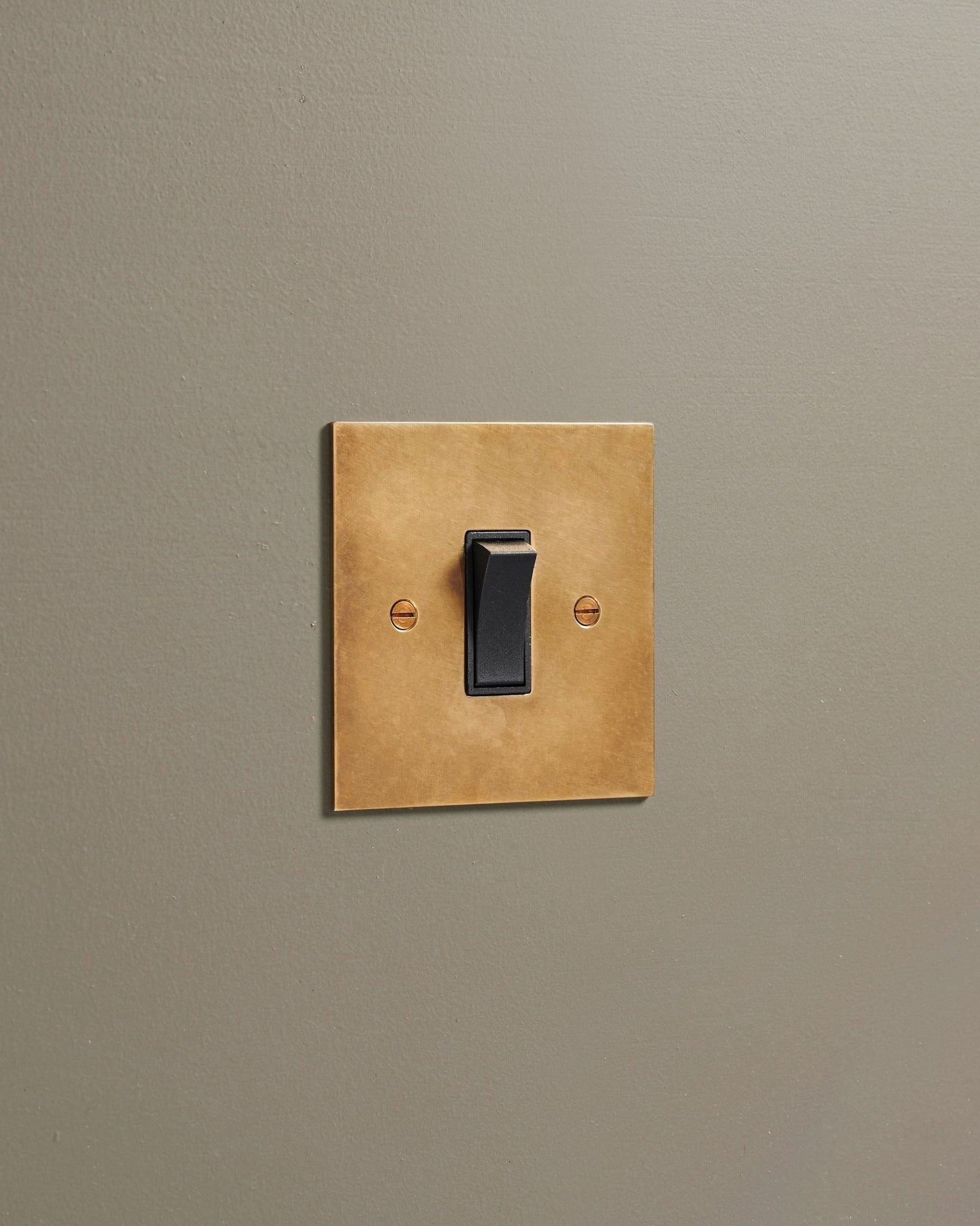 An oblique view of a classic 20 amp switch in a warm burnished brass finish.