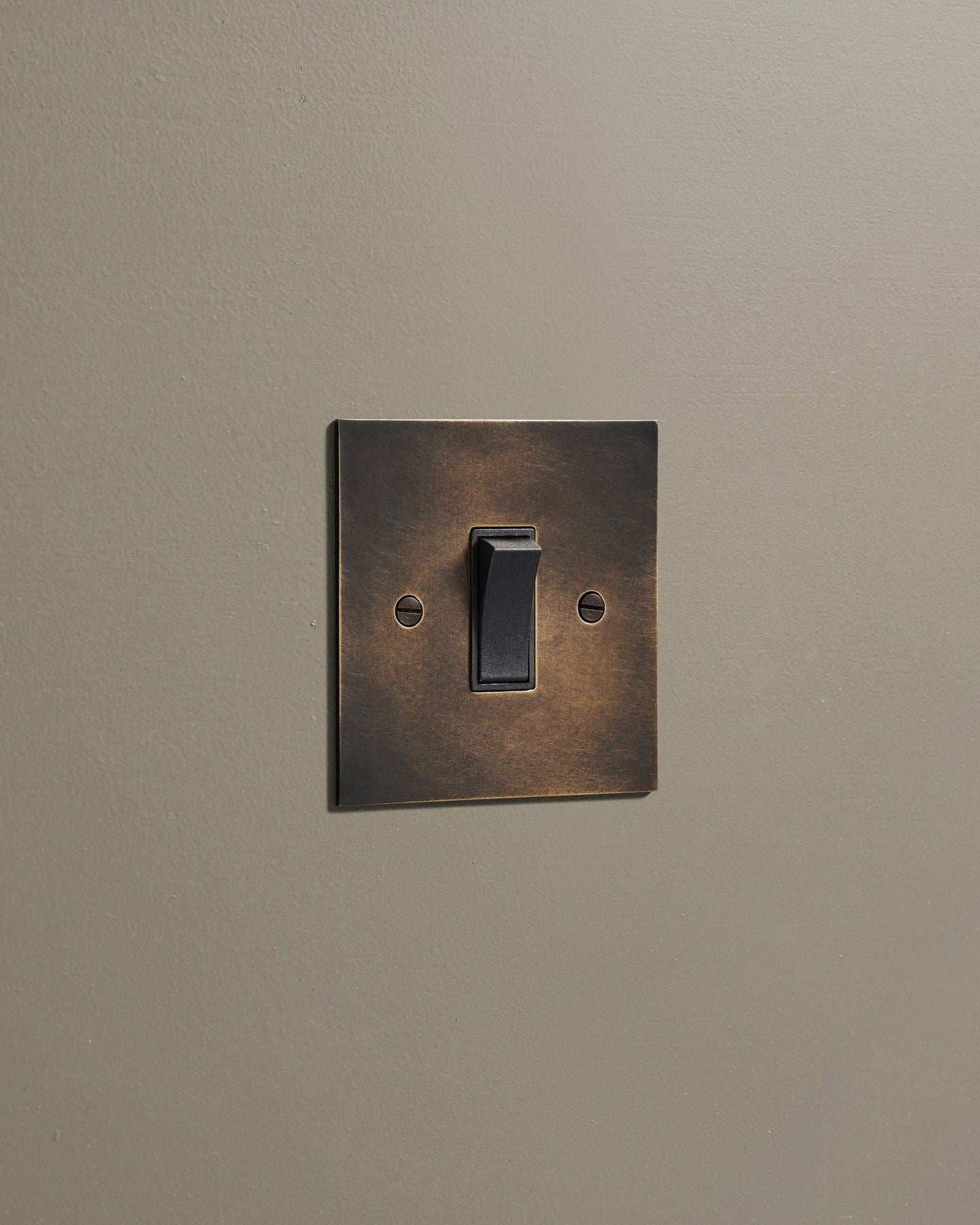 An oblique view of a classic 20 amp switch in a dark oxidised brass finish.