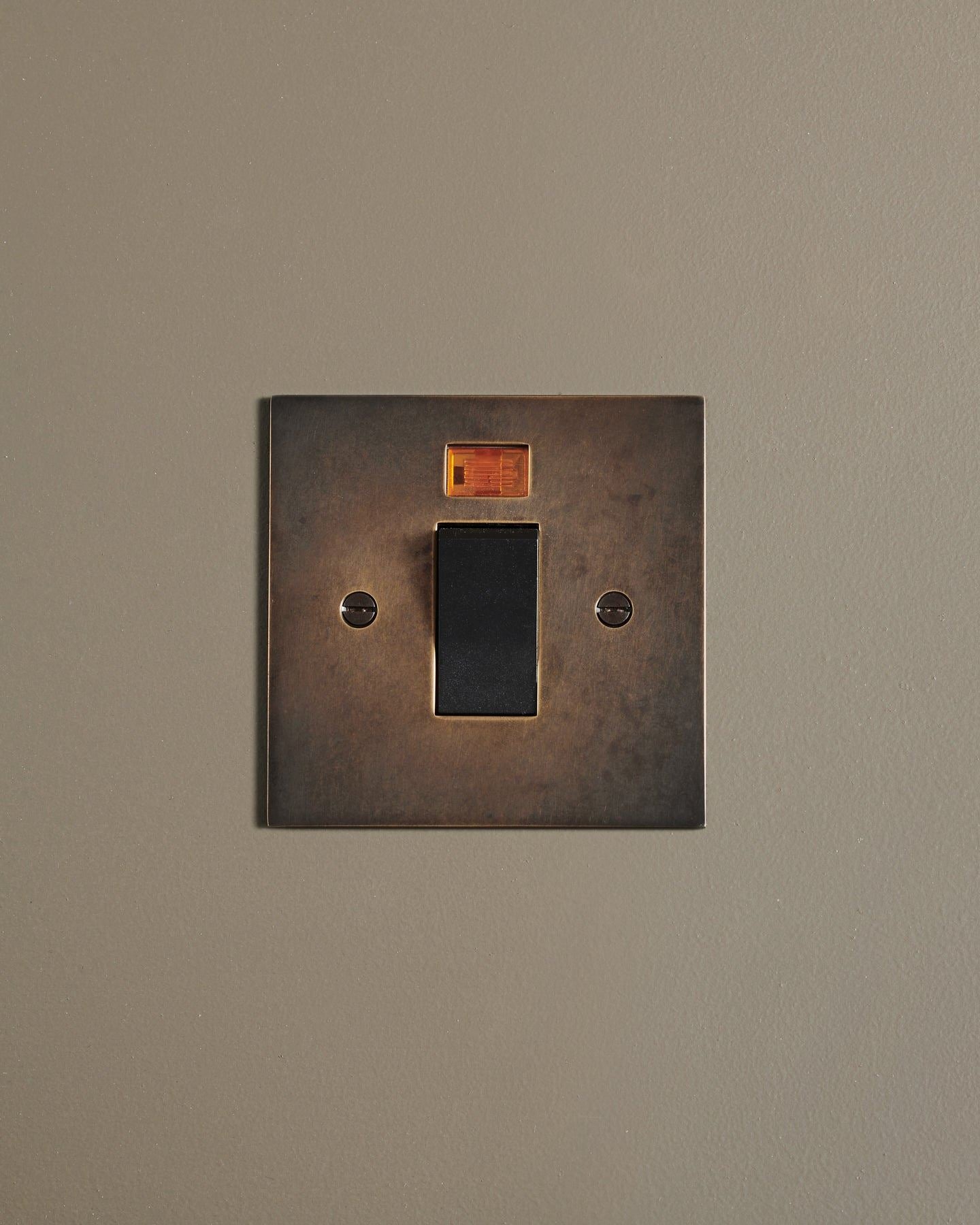 A straight-on view of a classic 45 amp cooker switch in a dark oxidised brass finish.