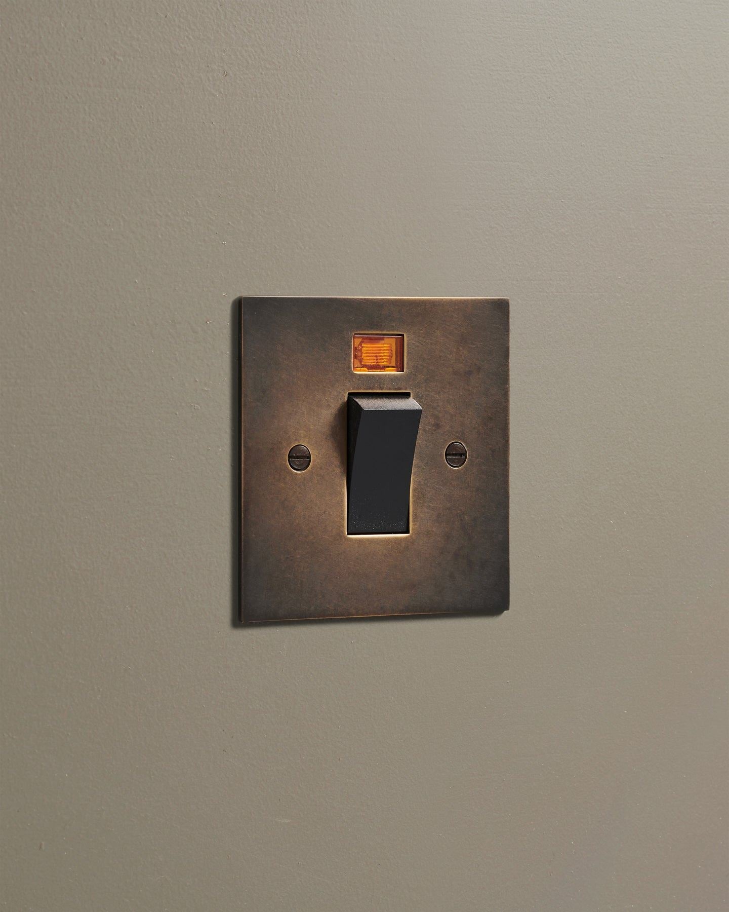 An oblique view of a classic 45 amp cooker switch in a dark oxidised brass finish.