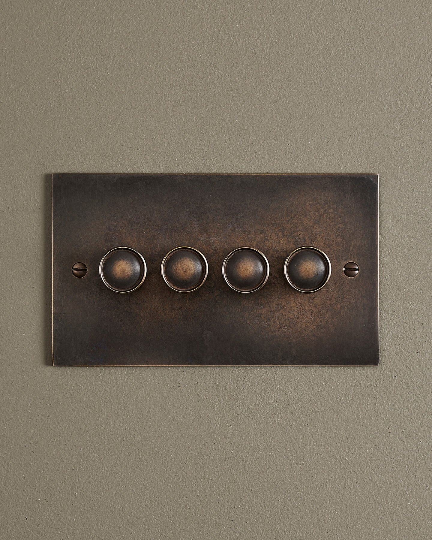 A straight-on view of a 4 gang classic dimmer switch in a dark oxidised brass finish.