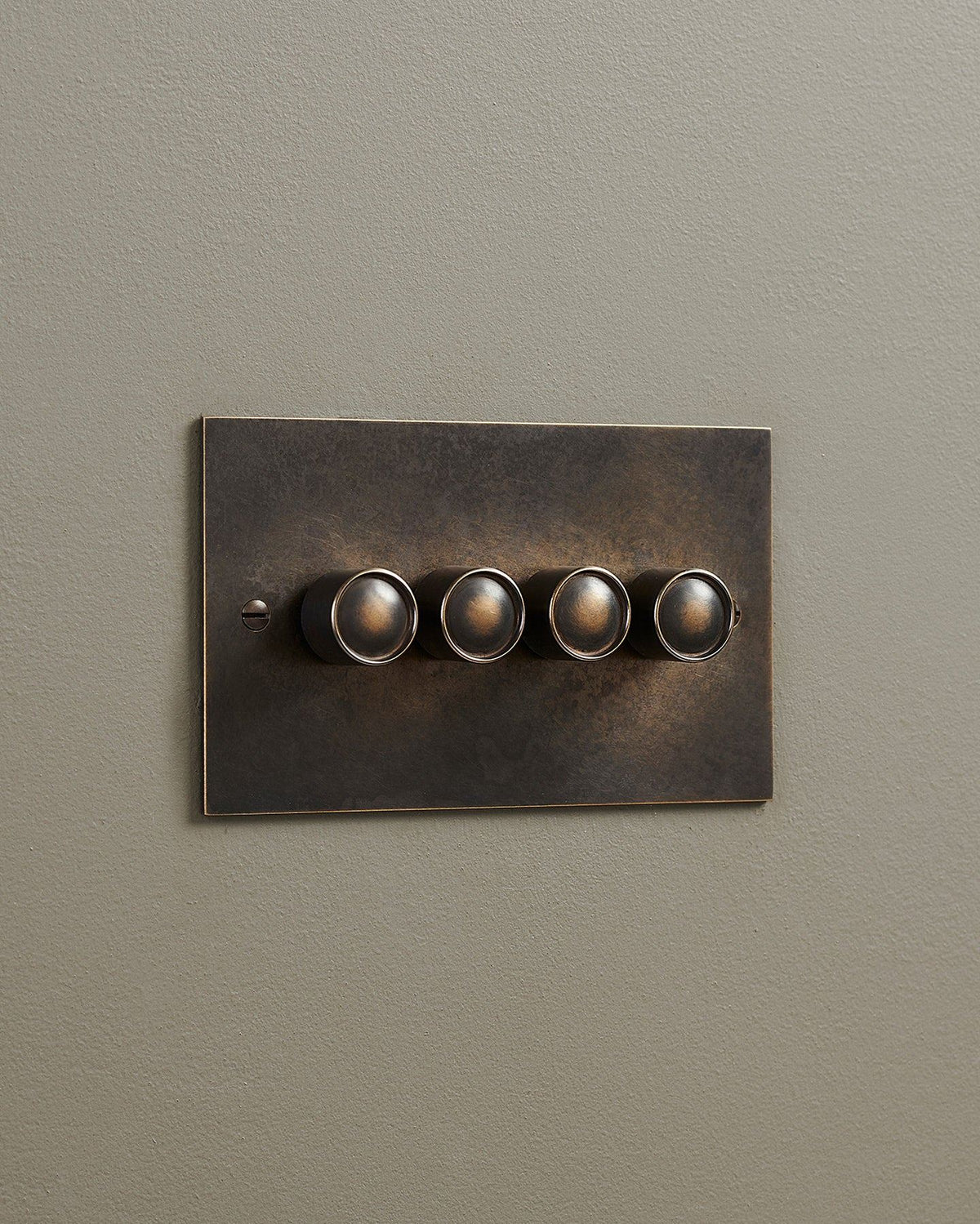 An oblique view of a 4 gang classic dimmer switch in a dark oxidised brass finish. TEST