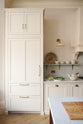 A quiet corner of the grand yet understated Classic English kitchen, this space features a dedicated cooker run with a canopy, a full-height cupboard, and an island. Styled with vintage artisan ceramics, and perfectly suited to relaxed, sociable living.