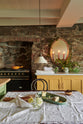 The quaint and glamorous cottage kitchen, in shades of green and scullery yellow, includes a marble-topped base cabinet. Lovingly decorated with vintage furniture, a sea green oval platter, wild flowers, and deVOL mini creamware lights, the space exudes personality and charm while respecting the cottage's original textures.