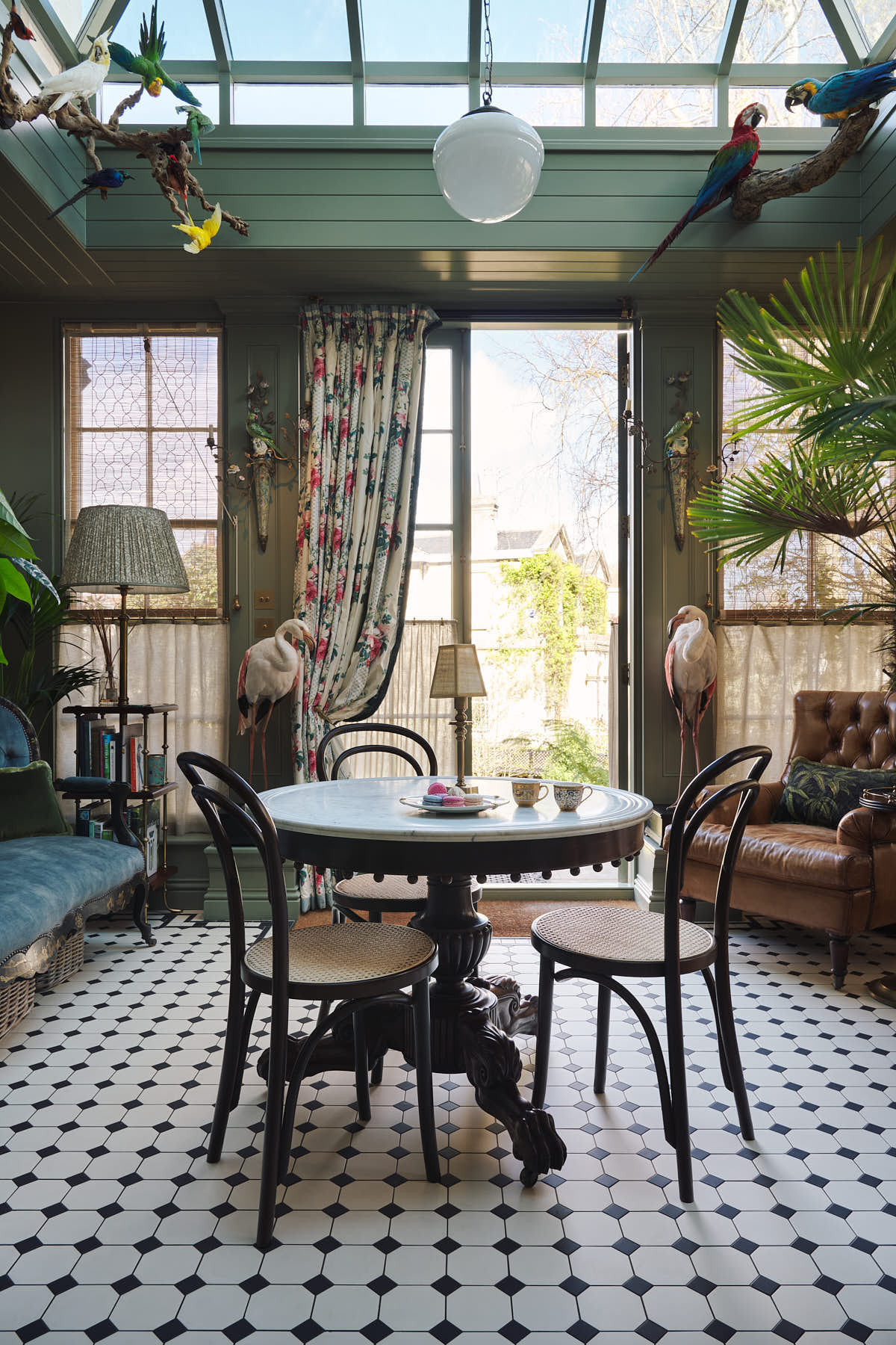 Opposite the eccentric yet grand Bakehouse Green Classic English Kitchen is a conservatory with a glass ceiling, marble floor, and an extravagant marble table with Bentwood Café chair. Pridefully displaying taxidermy, large indoor plants, and collectable antiques, it embraces a unique museum-like social space.