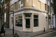 A tall historical townhouse, located at a corner in the heart of London, has been beautifully renovated in a shade known as Princelet pink. The building still showcases its original brick texture. Above the entrance door is the deVOL logo in black with a gold-rimmed shadow.