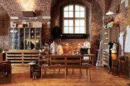 A handsome range of oak furniture and lighting from the deVOL Haberdasher’s collection features a kitchen island, countertop cupboards, and a glazed freestanding pantry. Adorned with deVOL Heirloom accessories, Helen stools, vintage furniture and items, dressmaker mannequins, and 1900s tailor tools, this space creates a beautiful homage to the English gentlemen’s haberdashery inspiration in a bricked wall showroom.