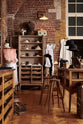 A handsome range of oak furniture and lighting from the deVOL Haberdasher’s collection features a kitchen island, countertop cupboards, and a glazed freestanding pantry. Adorned with deVOL Heirloom accessories, Helen stools, vintage furniture and items, dressmaker mannequins, and 1900s tailor tools, this space creates a beautiful homage to the English gentlemen’s haberdashery inspiration in a bricked wall showroom.