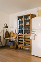 A closer look at a warm and spacious Haberdasher’s kitchen featuring a freestanding pantry with glazed doors. Adorned with vintage furniture and items, artisan ceramics, wicker baskets, tea towels, large wooden tapas boards, and wooden letterpress, this kitchen creates a contemporary yet nostalgic space.
