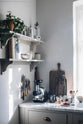 A cosy corner in the Mushroom Shaker kitchen with a Carrara marble worktop, a juicer, wooden chopping boards, and shelves of books, ceramics, and plants.