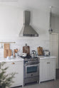 A close, angled view at the silver gas stove with matching chimney cooker hood of the Mushroom colour shaker kitchen with Carrara marble worktop.