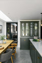 A bright and sophisticated Bakehouse Green shaker kitchen, styled with Scandinavian furniture and a soothing green palette. The kitchen features a central island with a double Belfast sink and a glazed larder with Silestone worktop. There’s a beautiful skylight above the solid oak dining table.